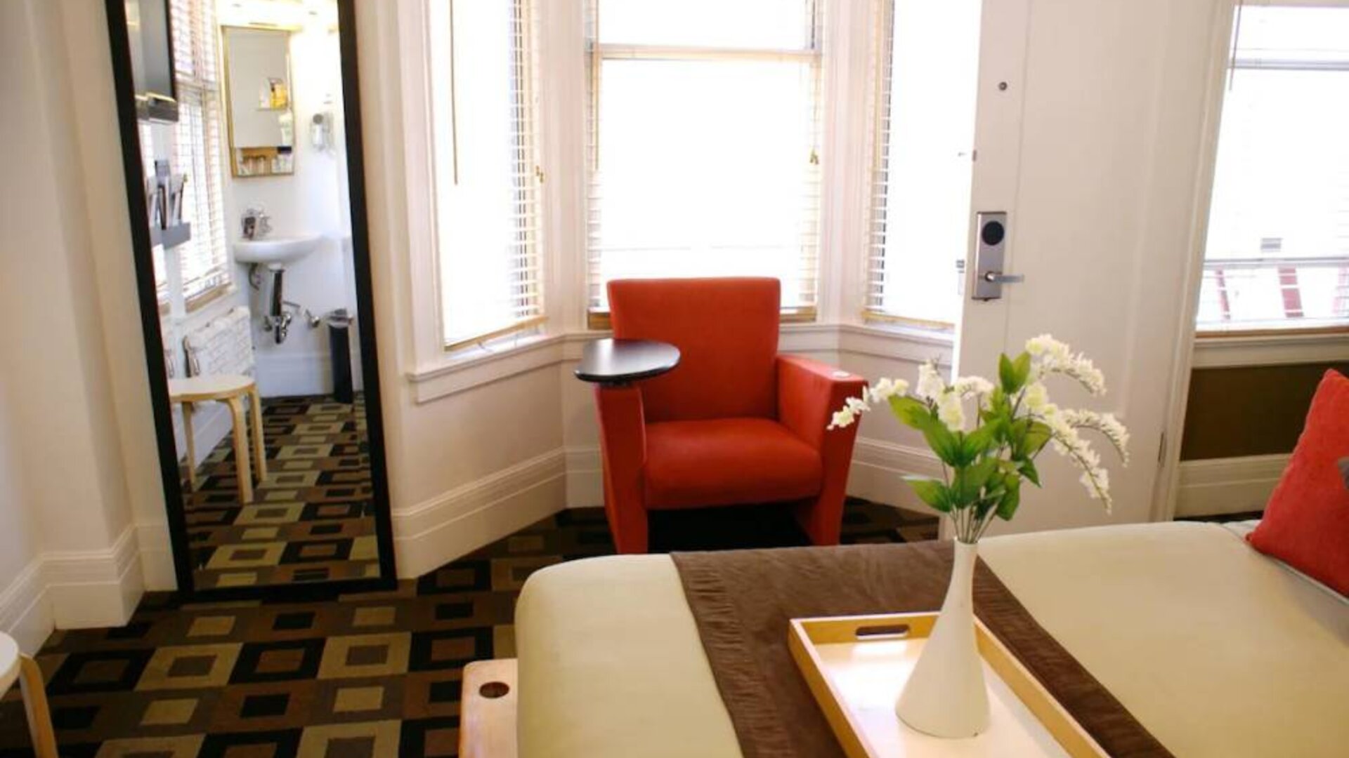 Guest room of The Mosser Hotel, with bed, chair, windows, and ensuite bathroom.