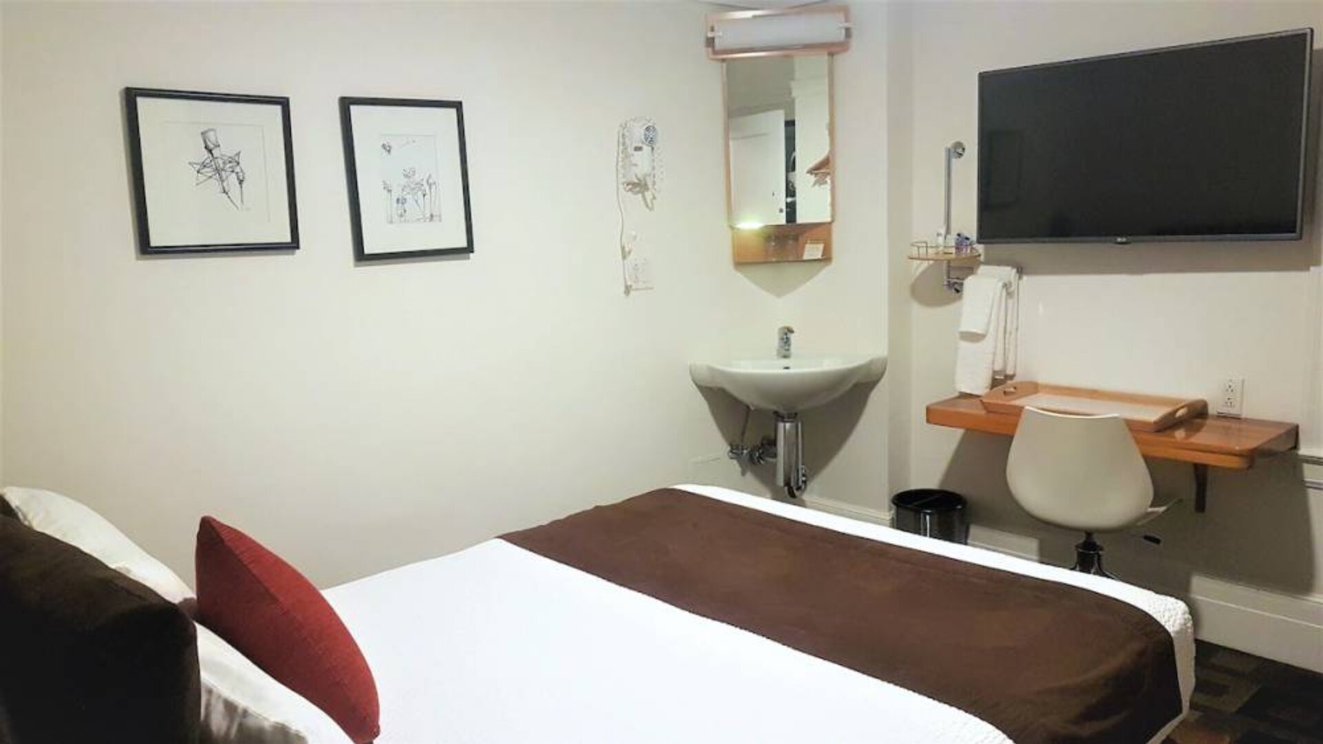 Guest room inside The Mosser Hotel, featuring a workspace desk and chair plus large TV.