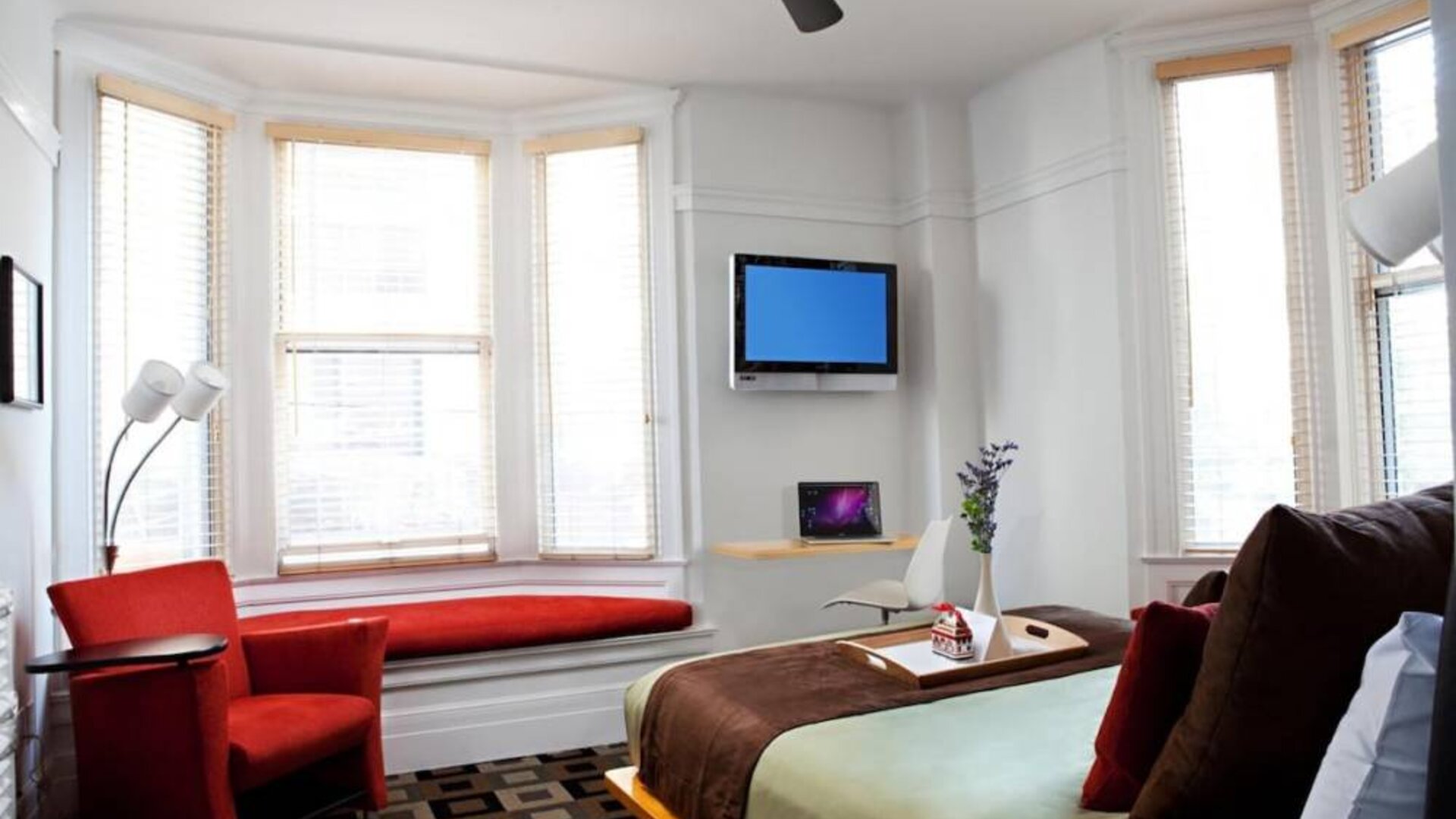 The Mosser Hotel guest room, including TV, chair, bed, and nearby window.