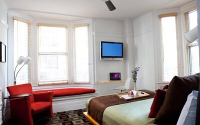 The Mosser Hotel guest room, including TV, chair, bed, and nearby window.