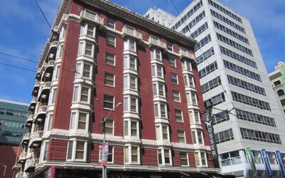 Exterior of the Mosser Hotel, with vertical sign and vibrant red brick hue.