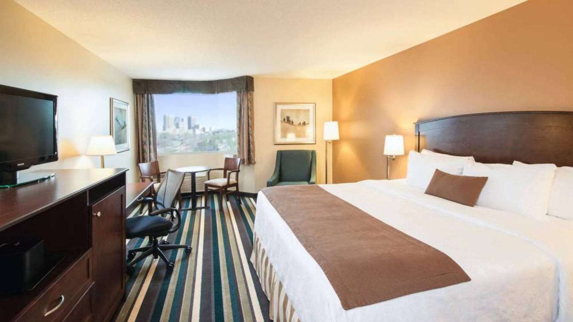 Best Western Plus Winnipeg Airport guest room, including large bed, and desk and chair for working.