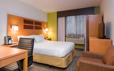 One of Holiday Inn Express Times Square’s guest rooms, with comfy chair, space for working, and window, plus double bed.