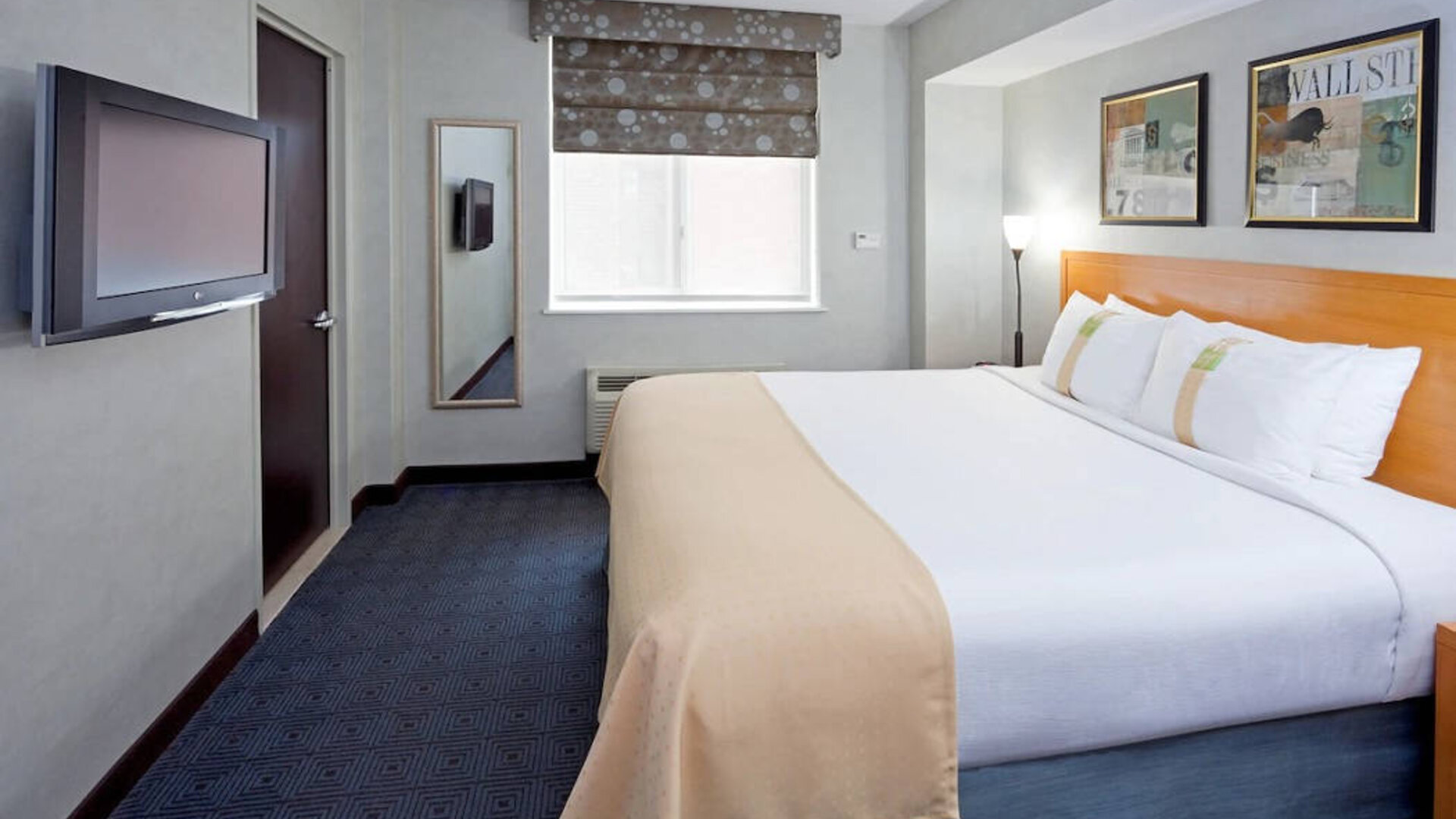 Double bed guest room in the Holiday Inn Express Wall Street, with window, TV, and mirror.