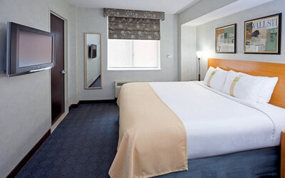 Double bed guest room in the Holiday Inn Express Wall Street, with window, TV, and mirror.