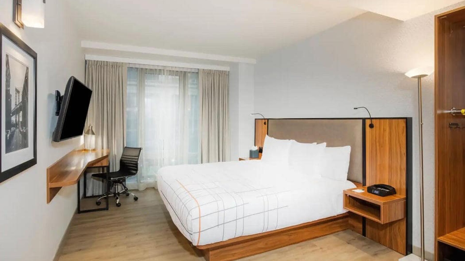 Guest room in La Quinta Times Square South, complete with double bed, large window, TV, and workspace.