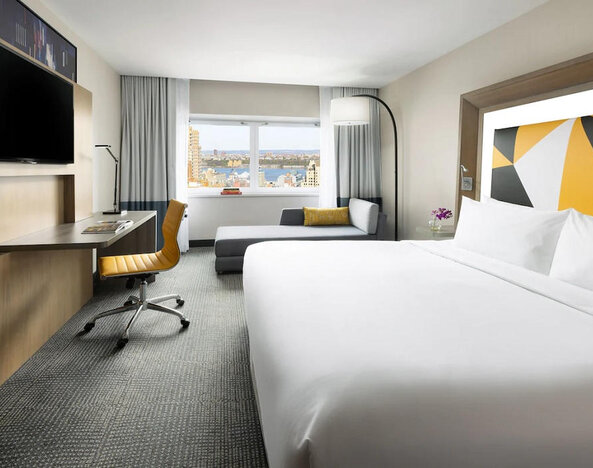 Spacious day use room with TV, business desk, and couch at M Social Hotel Times Square.
