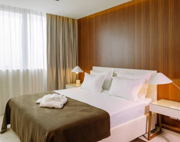 Day room with ample natural light, a double bed and a bedside lamp.