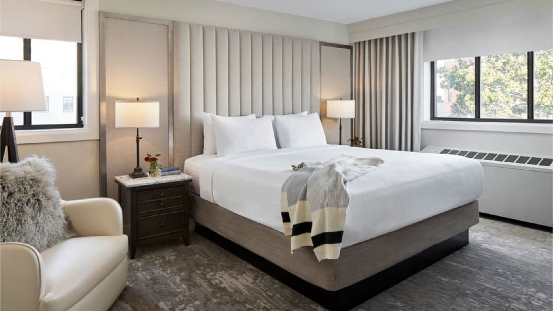 Delux king bed with chair and natural light at Capitol Hill Hotel.