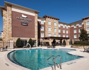 Lovely outdoor pool with seating area at Homewood Suites By Hilton Denton.