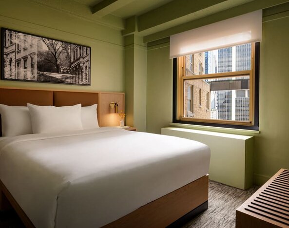 Guest room with natural light, city views, and minimalist modern furnishings at Row NYC.