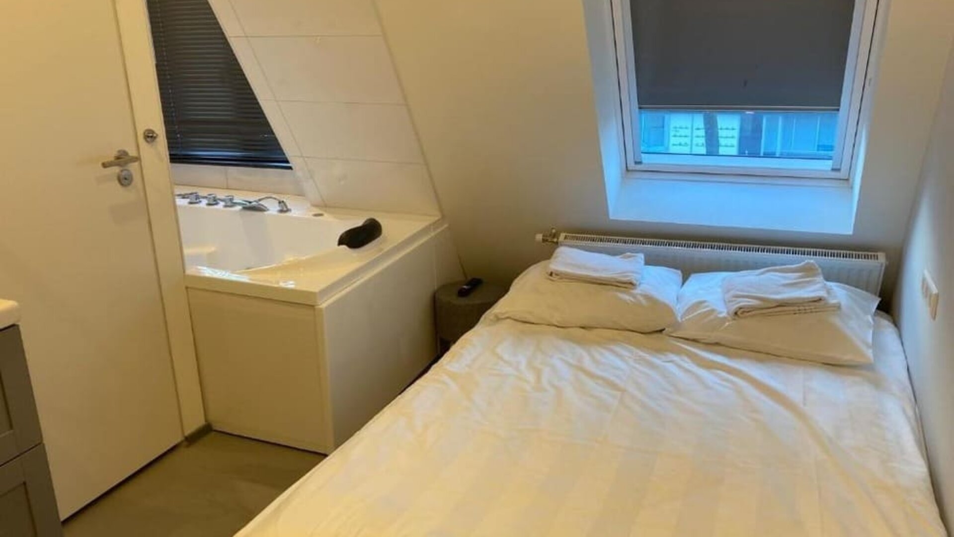 Cozy guest room with a double bed, whirlpool bathtub, skylight window, and fresh linens at Hotel Chao 24/7.