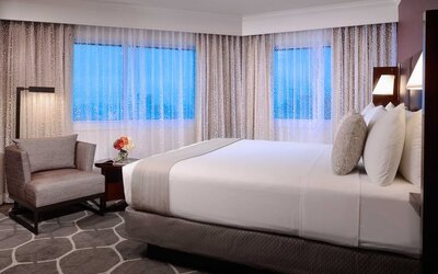 Royal Sonesta Houston Galleria king bed guest room, including windows, armchair, and coffee table.