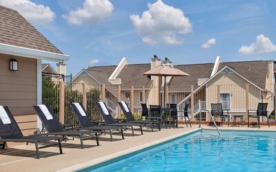 Sonesta ES Suites Tucson’s outdoor pool has a row of sun loungers, plus tables and chairs, by the side.