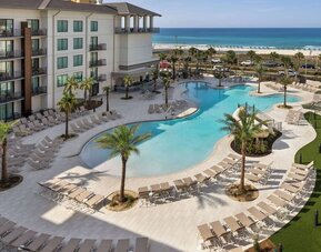 Beautiful outdoor pool with lounge chairs at Embassy Suites By Hilton Panama City Beach Resort.