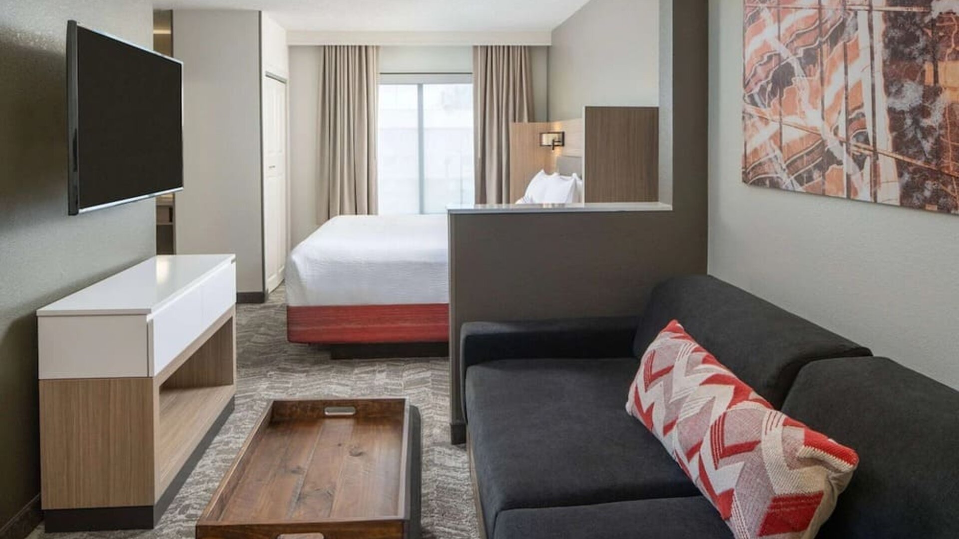 King bed guest room in Sonesta Select Nashville Airport Suites, furnished with sofa, television, and window.