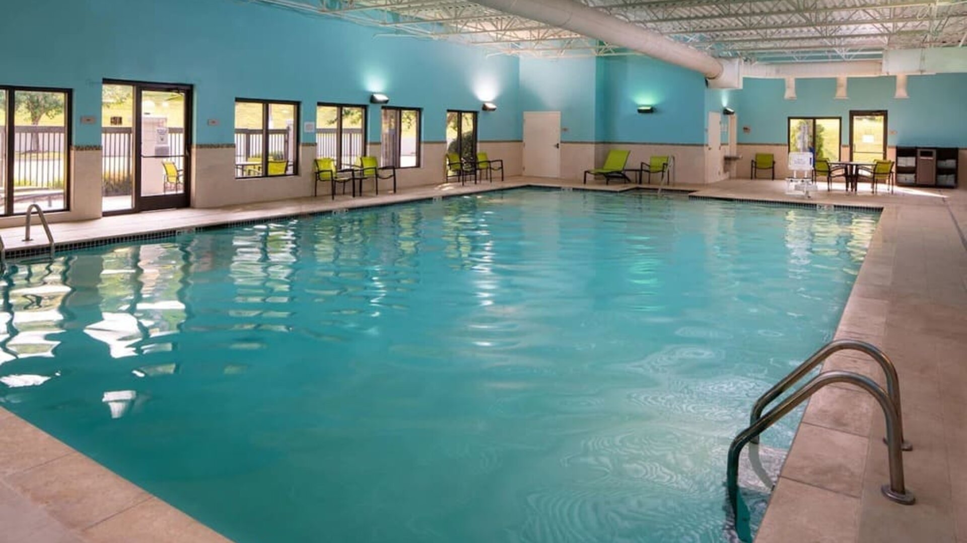 Sonesta Select Nashville Airport Suites’ indoor pool is brightly lit, has chairs by the side, and is adjacent to the patio.