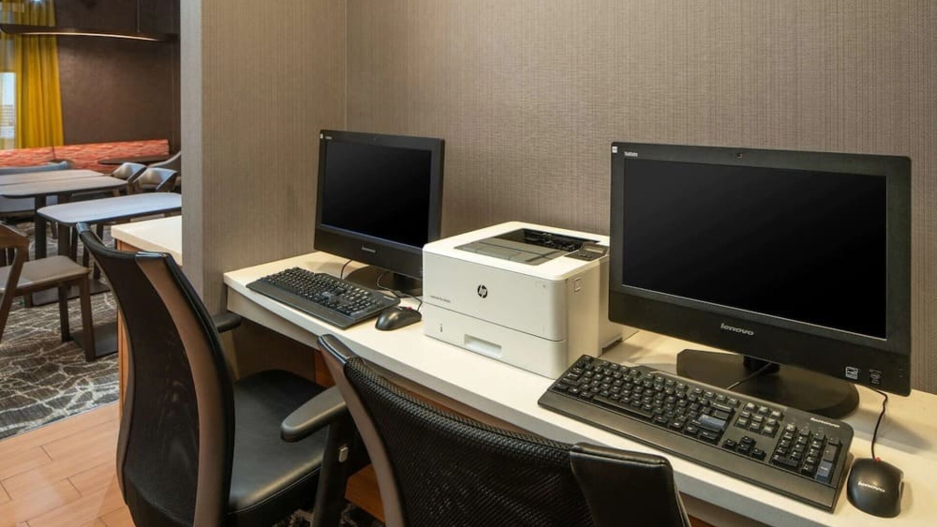 The hotel business center includes a pair of computer workstations and a printer.