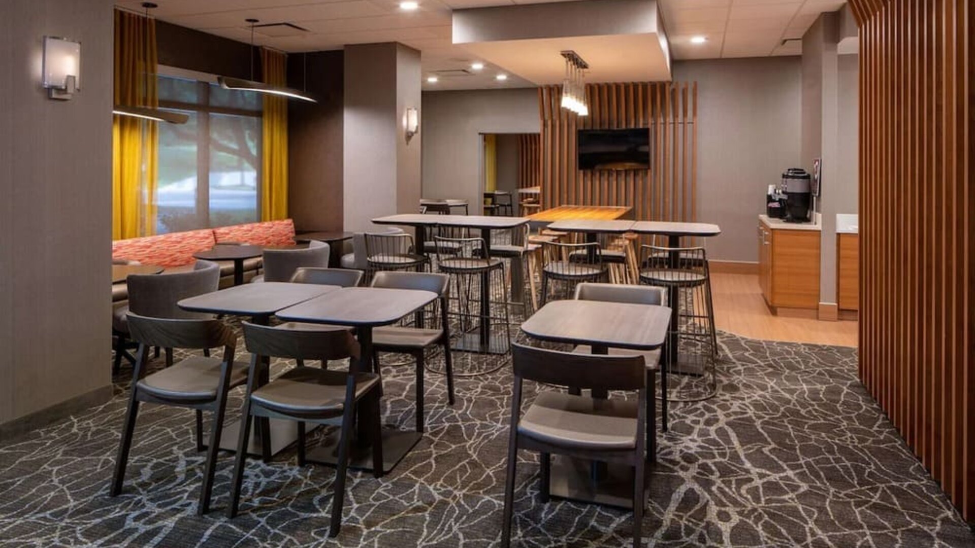 Hotel workspace, including extensive seating and tables for between two and six individuals, and coffee-making facilities.