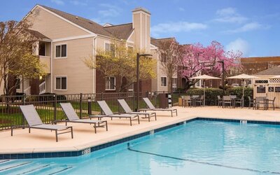 Shaded tables and chairs, as well as sun loungers, are by the side of Sonesta ES Suites Nashville Brentwood’s outdoor pool.
