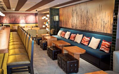 The hotel bar has a mix of traditional tall stools and table seating, and a hard floor.