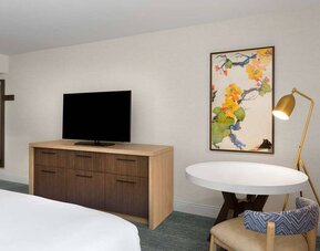 Double bed guest room in Sonesta Silicon Valley, furnished with widescreen television, and workspace desk, chair, and lamp.