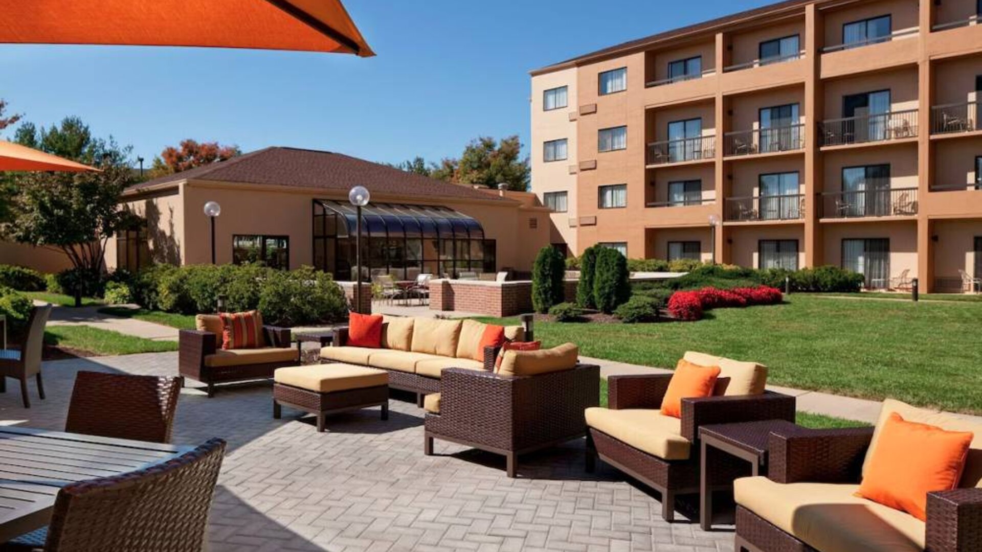 The hotel terrace is furnished with shaded tables and chairs, plus armchairs and sofa seating with adjacent coffee tables.