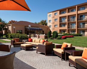 The hotel terrace is furnished with shaded tables and chairs, plus armchairs and sofa seating with adjacent coffee tables.