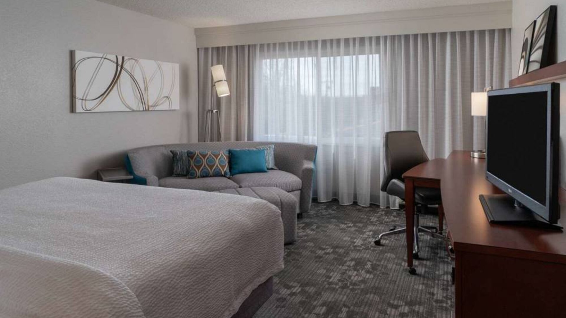 Double bed guest room in Sonesta Select Chattanooga Hamilton Place, featuring sofa, TV, desk, and window.