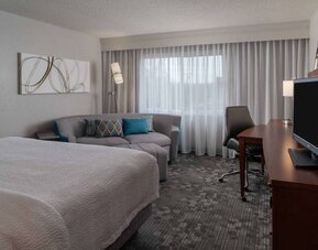 Double bed guest room in Sonesta Select Chattanooga Hamilton Place, featuring sofa, TV, desk, and window.