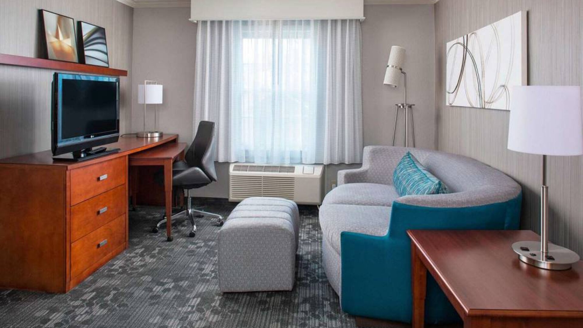 Sonesta Select Boston Lowell Chelmsford guest room lounge, furnished with sofa, chair, and TV.