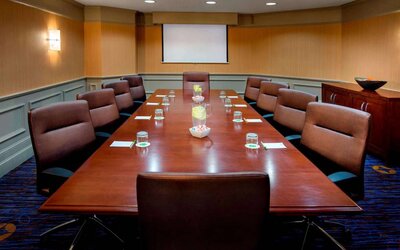 Sonesta Select Boston Danvers meeting room, with ten swivel chairs around a long table, and a projector screen.