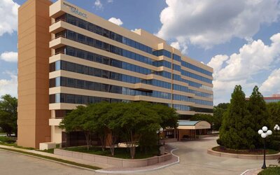 Sonesta Select Atlanta Cumberland Galleria’s exterior has the name on the building, numerous trees, and a covered entranceway.