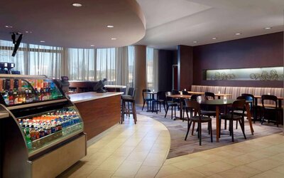 Sonesta Select Atlanta Cumberland Galleria’s dining area features a bar, both tall stool and table seating, and large windows.