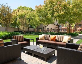 The hotel’s patio has trees nearby, and a mix of sofa and armchair seating.