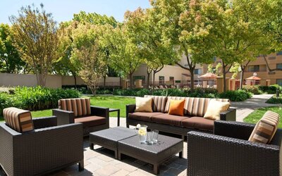 The hotel’s patio has trees nearby, and a mix of sofa and armchair seating.