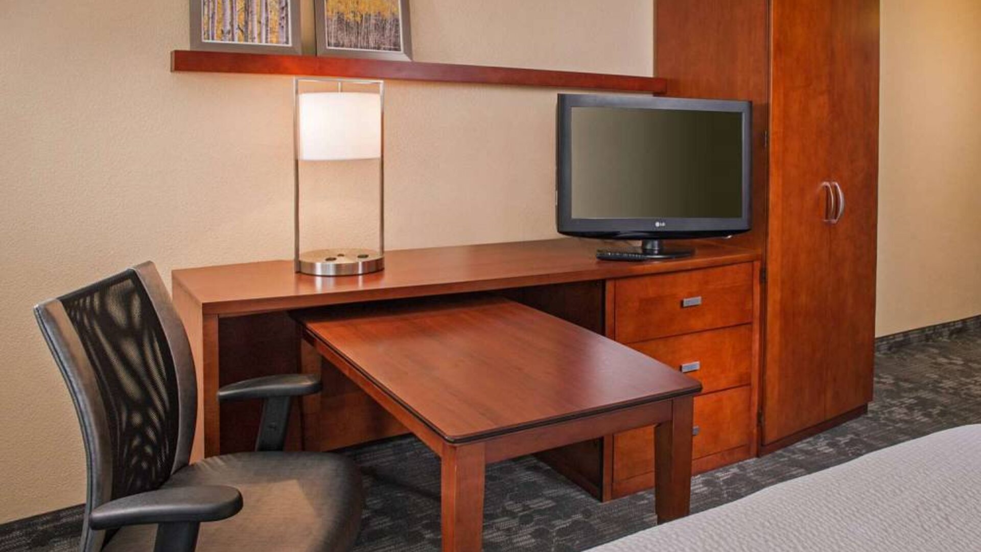 Guest room workspace in Sonesta Select Charlotte University Research Park, including desk, chair, and television.