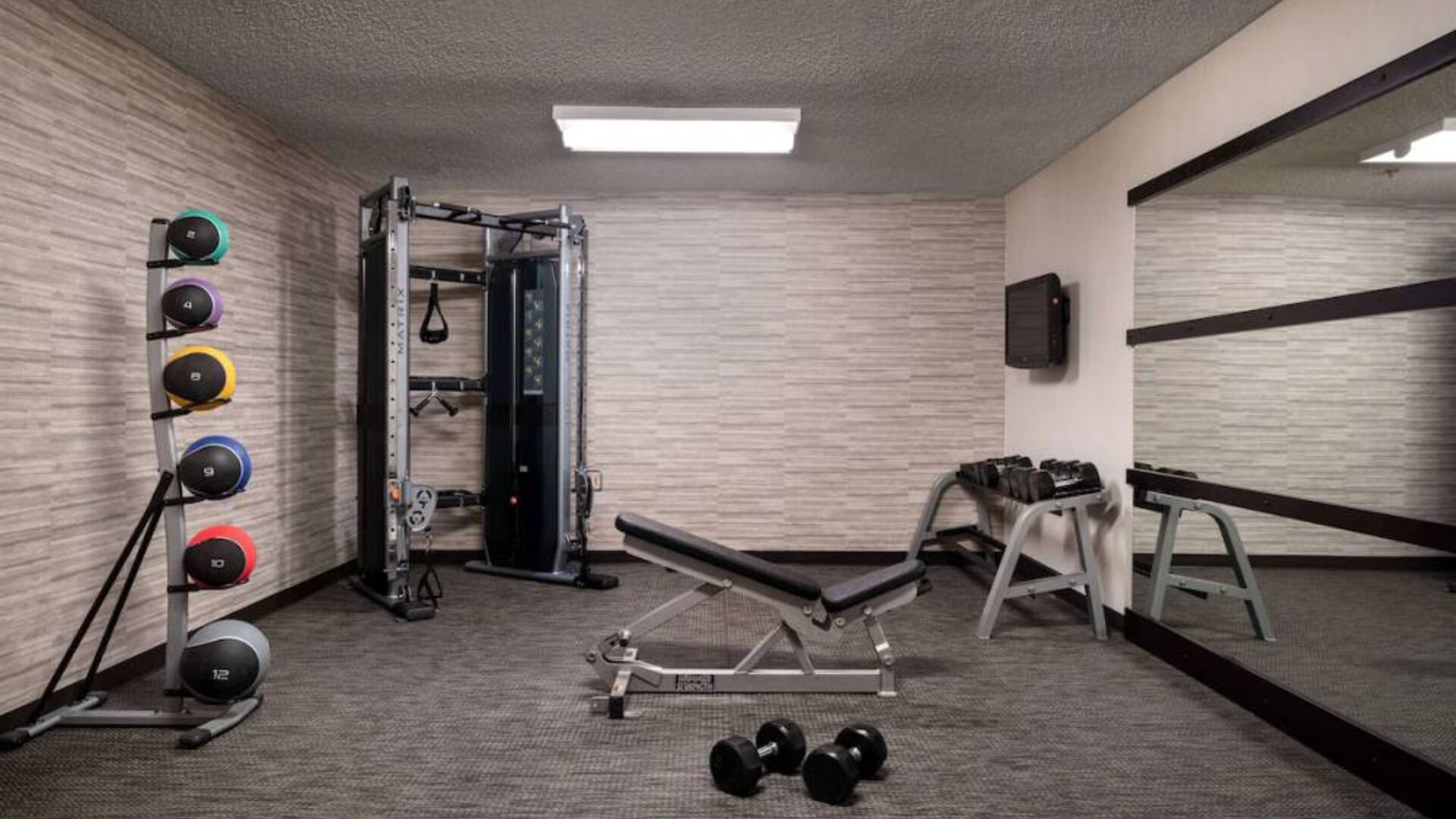 Sonesta Select Charlotte University Research Park’s fitness center is equipped with free weights, a bench, wall-mounted TV, and gym balls.