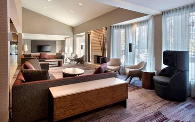 The lobby lounge in Sonesta Select Boston Milford includes chairs, sofas, and coffee tables, plus large windows.