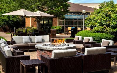 The hotel’s fire pit is surrounded by sofas and armchairs, and plenty of coffee tables, with pleasant greenery in the background.