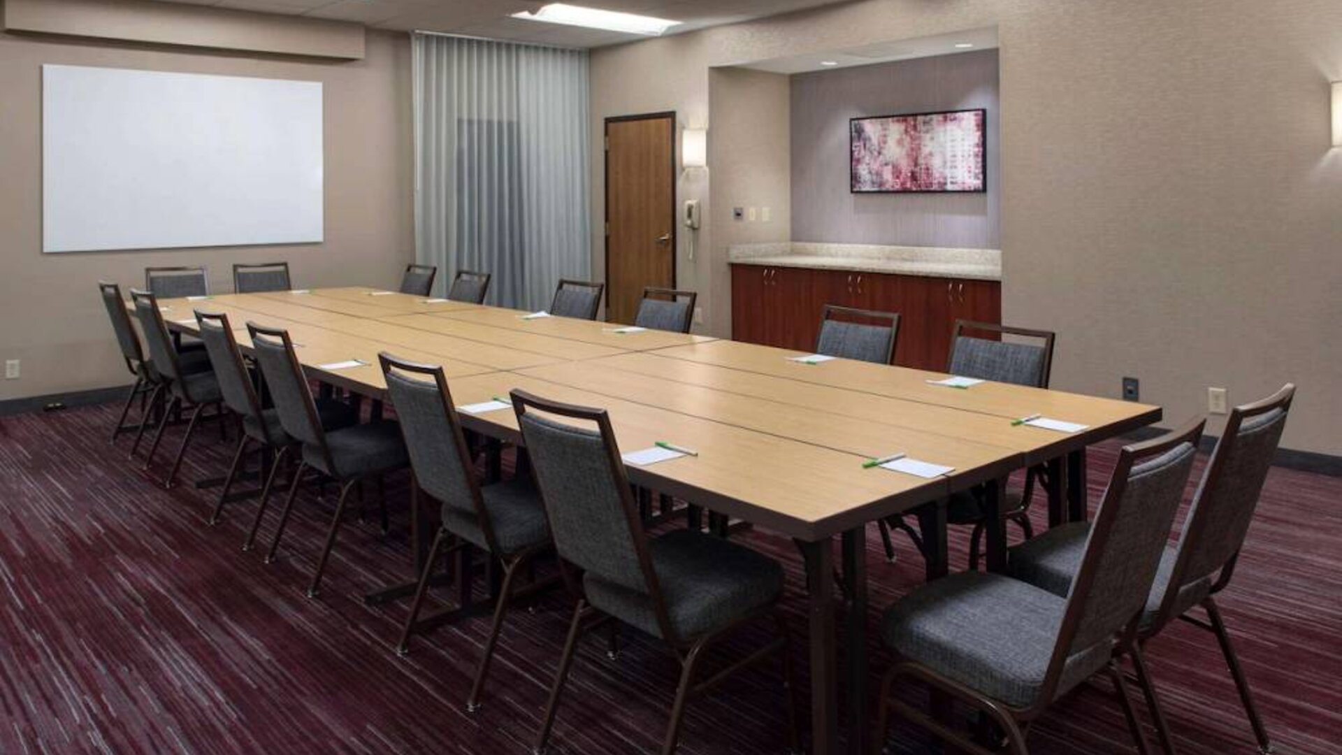 Meeting room in Sonesta Select Boston Milford, furnished with seating for 16 attendees, a long table, and a whiteboard.