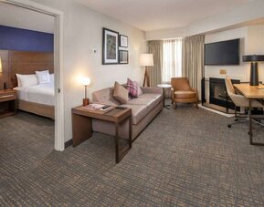 Double bed guest room in Sonesta ES Suites Baltimore BWI Airport, furnished with sofa, chair, fireplace, and television.