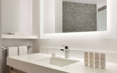 Guest bathroom in the hotel, including a range of toiletries, towels, and a sink.