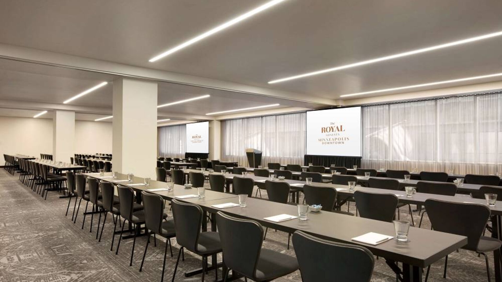 Large meeting room in Royal Sonesta Minneapolis Downtown, with lectern, large screens, and space for seating for several dozen attendees.