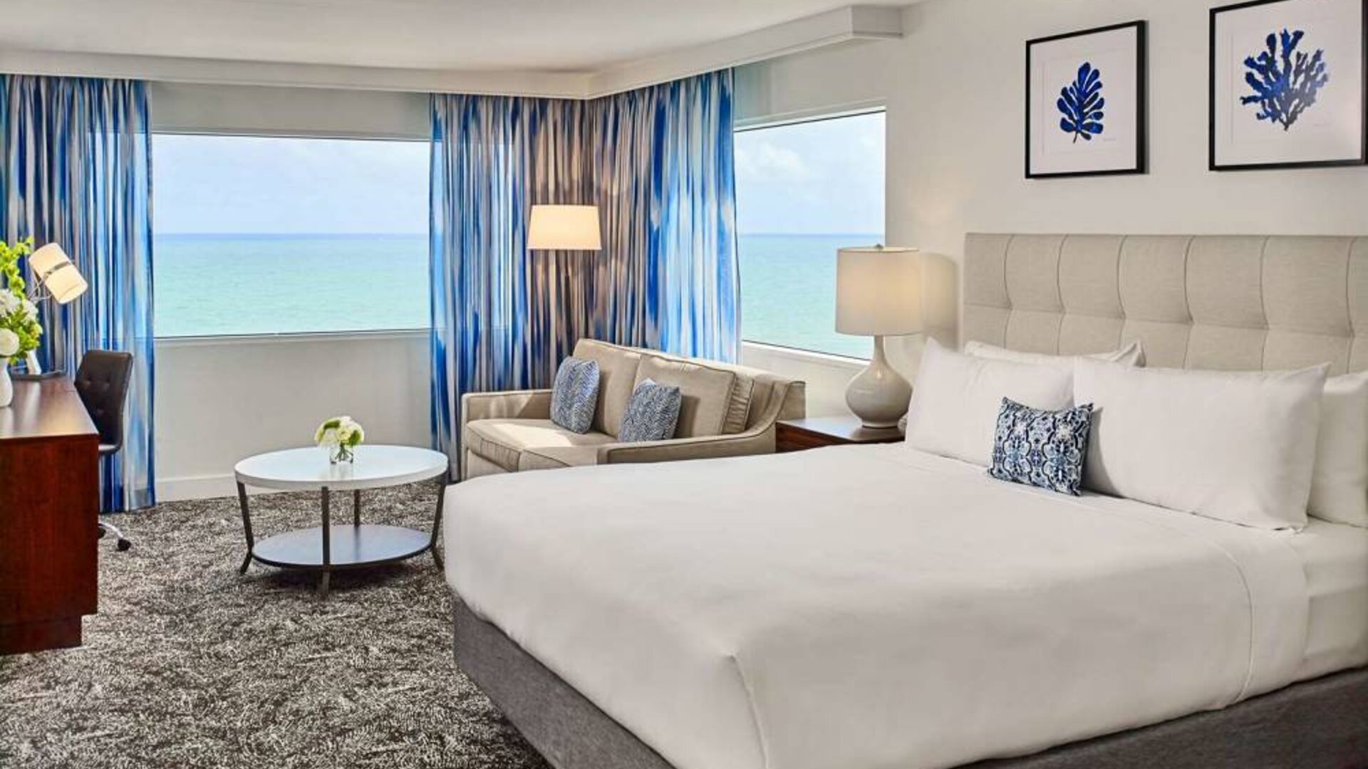 Sonesta Fort Lauderdale Beach double bed guest room, featuring ocean views, a sofa, coffee table, and workspace.