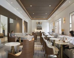 The hotel’s living room is furnished with comfortable seating and small tables, where guests can socialize, co-work, or have a drink.