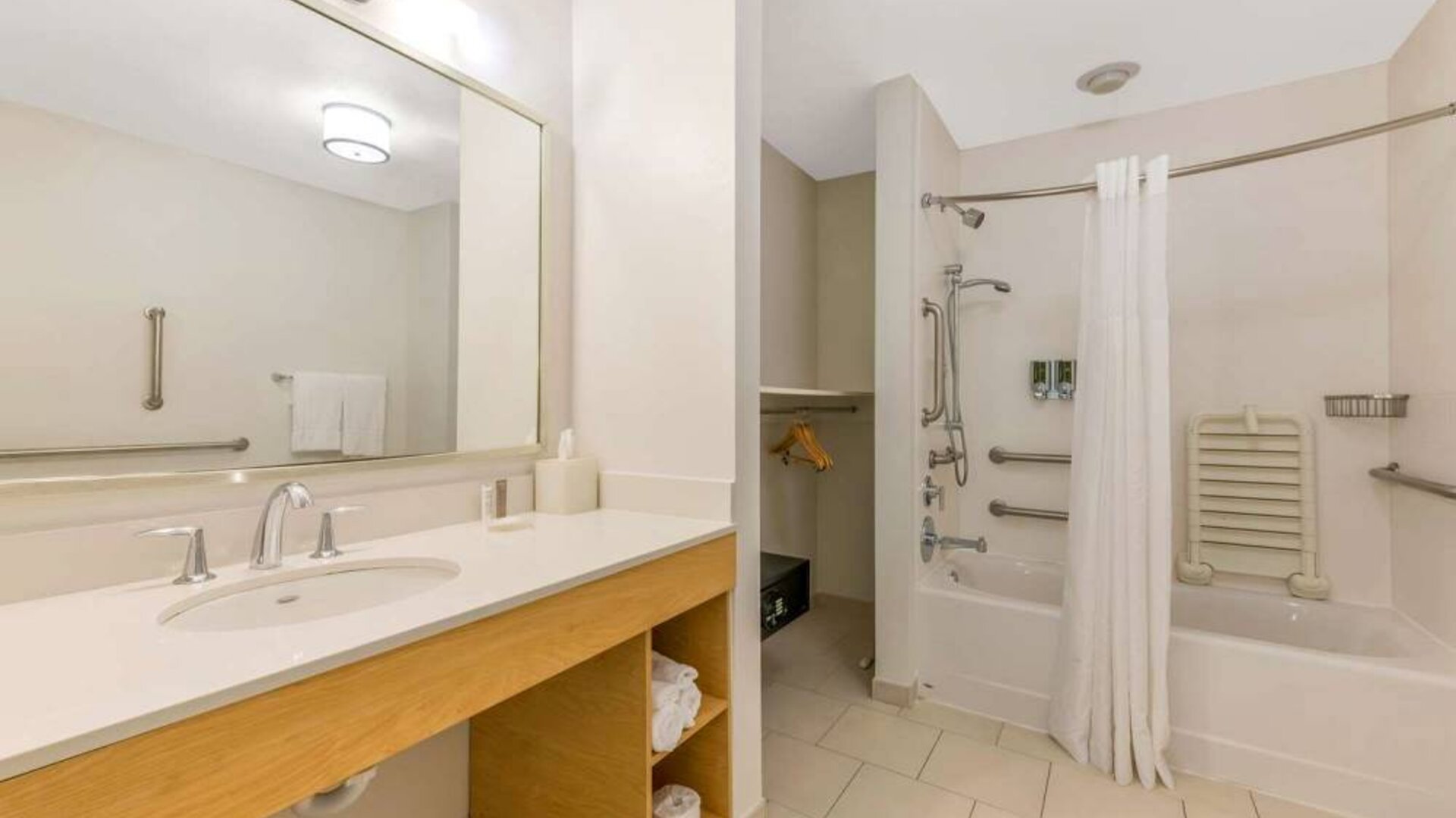 Guest bathroom in Sonesta ES Suites Charlotte Arrowood, furnished with large mirror, sink, bath and shower.