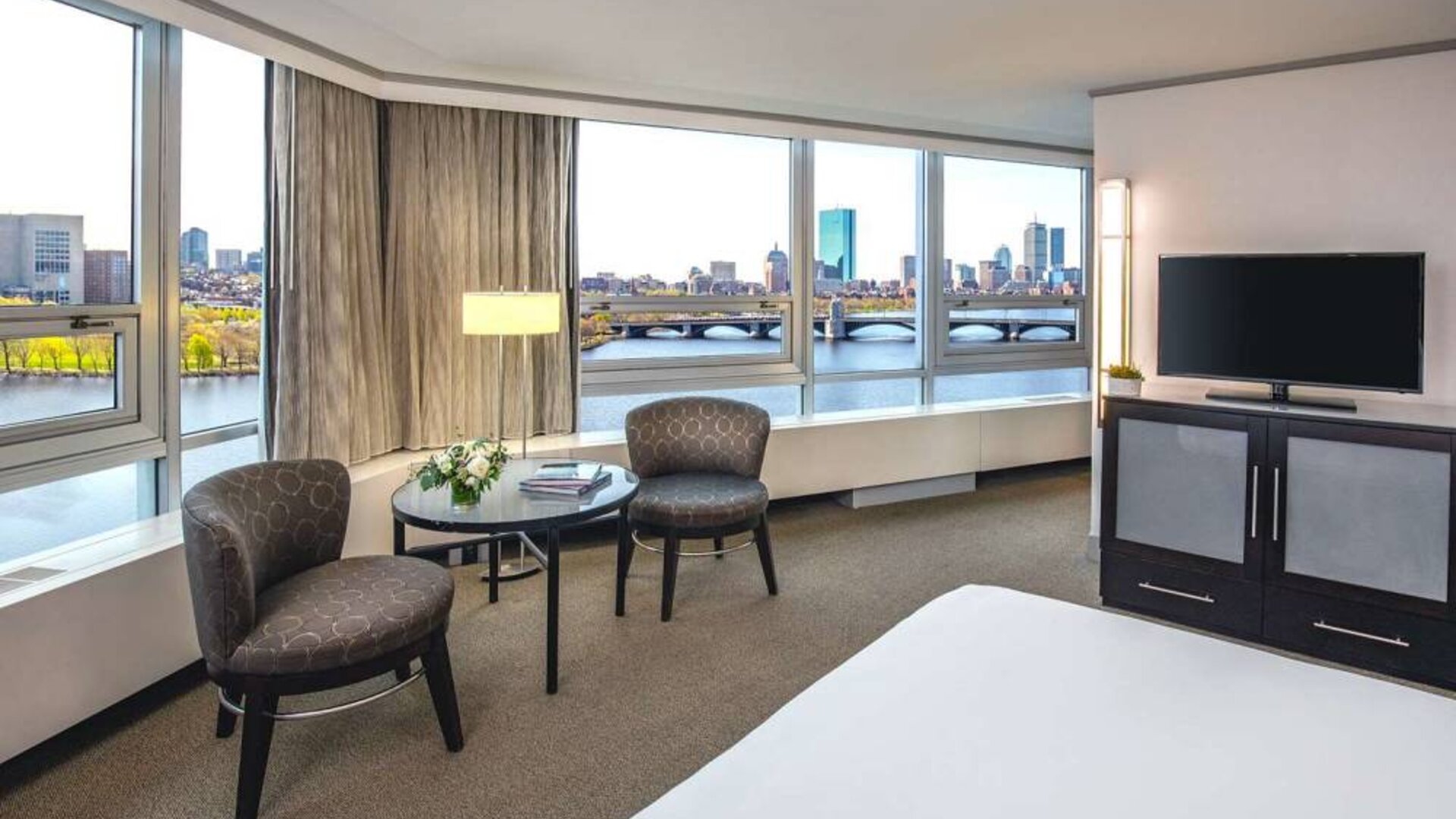 Royal Sonesta Boston double bed guest room, featuring wonderful city views, a widescreen TV, two chairs, and a coffee table.