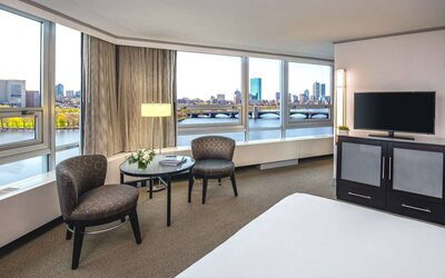 Royal Sonesta Boston double bed guest room, featuring wonderful city views, a widescreen TV, two chairs, and a coffee table.
