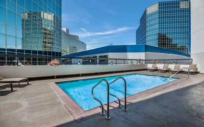 Sonesta Los Angeles Airport LAX’s outdoor pool has loungers by the side and towering buildings nearby.